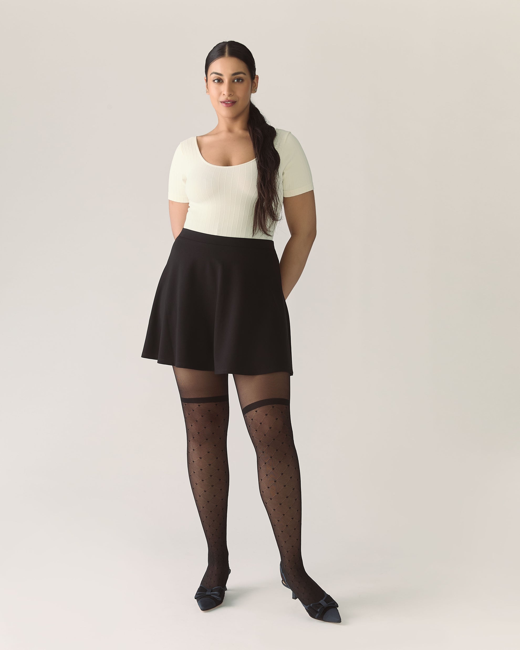 Woman wearing a white top, black skirt, and black stockings