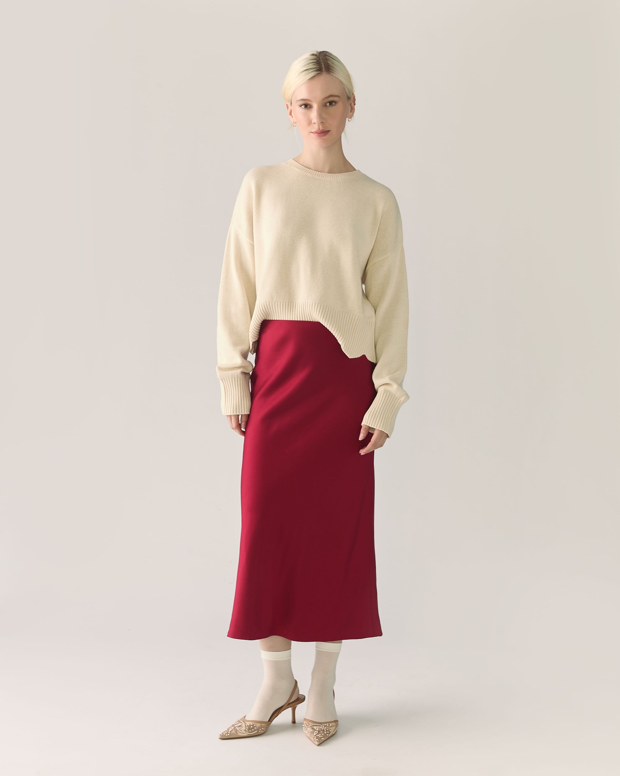 Woman wearing a beige sweater and red pomegranate skirt