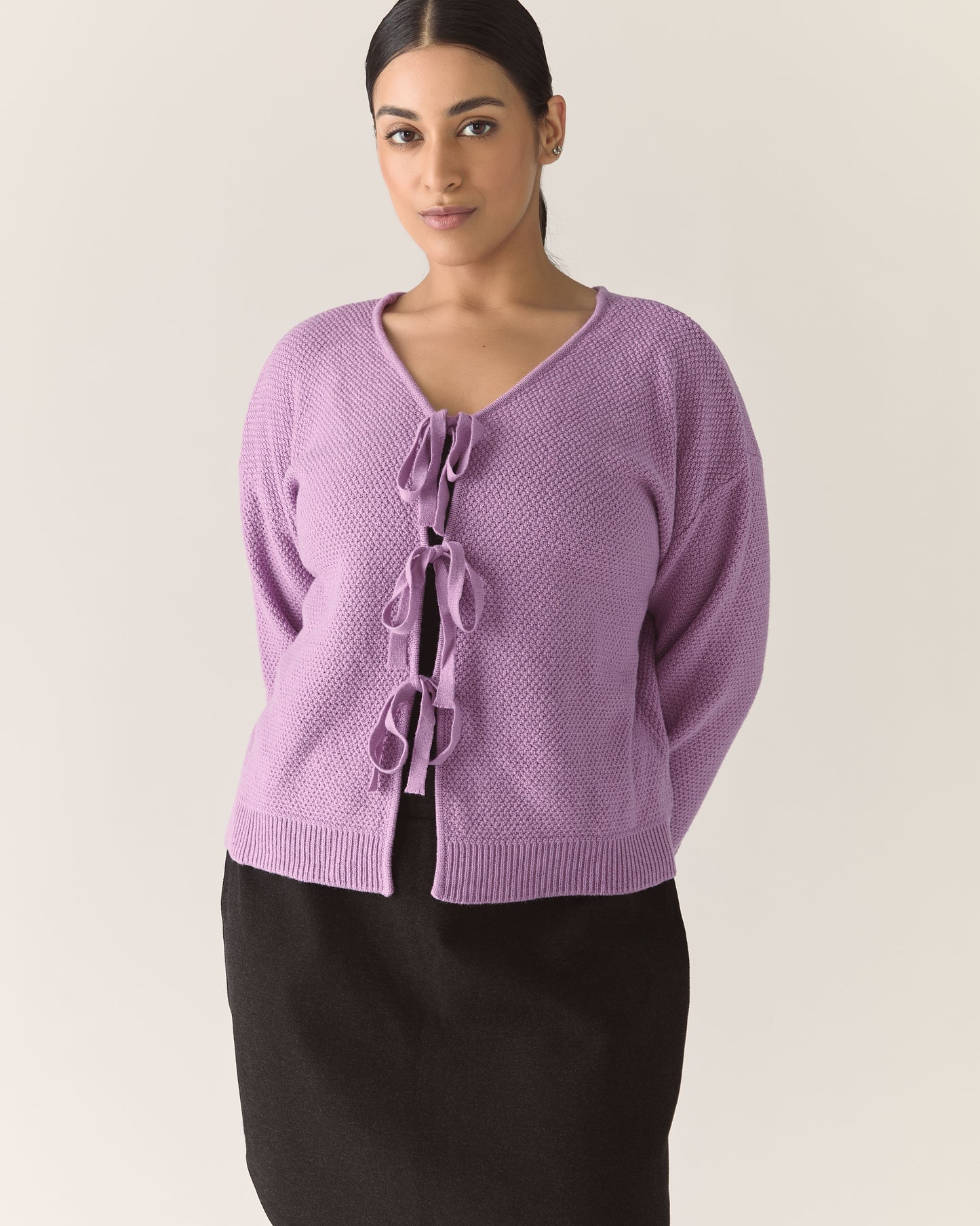 Woman wearing a purple lilac knitted cardigan with a tie bows detail 