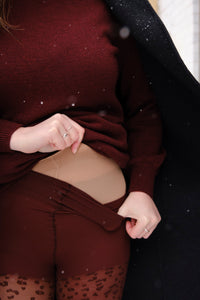 Person wearing a burgundy sweater and patterned tights with a focus on the layering with fleece tights